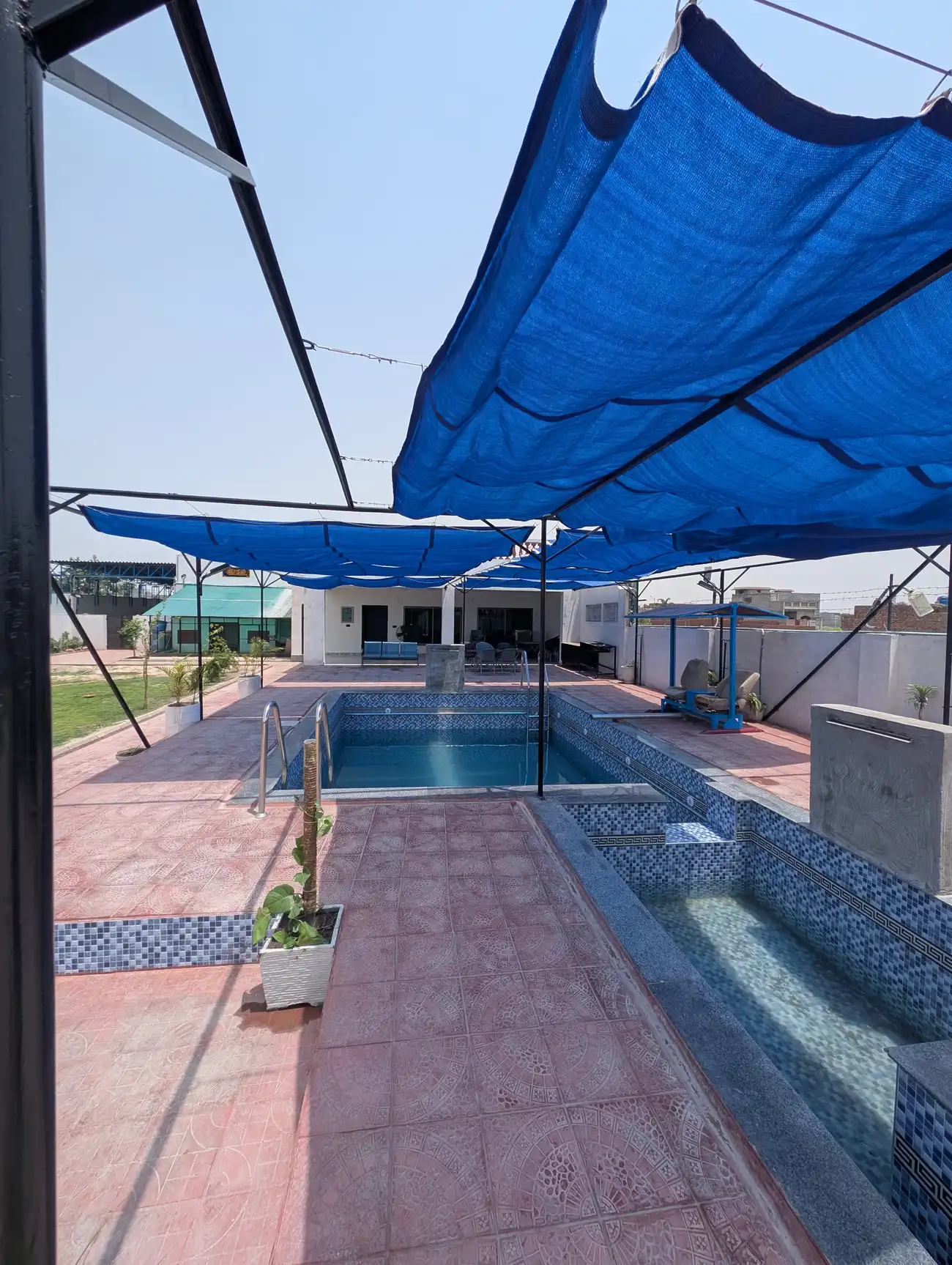 Kosam Farms shaded swimming pool and tiled terrace seating area